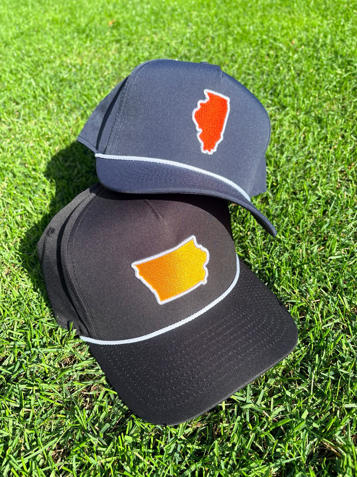 Navy Illinois and black Iowa State Line embroidered rope hats on the grass.